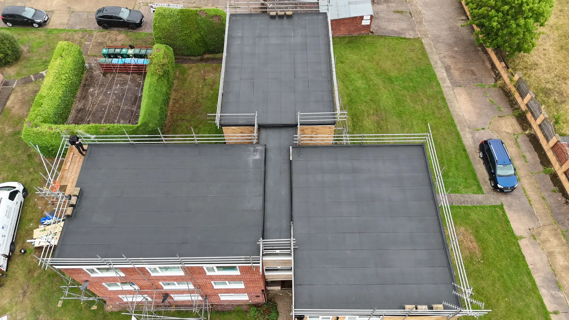 The same block of flats after new dark single-ply flat roofing was installed, with scaffolding in place