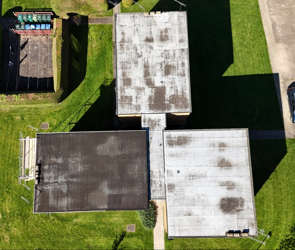 Aerial view of three weathered, stained flat roofs on a block of flats before replacement in Coventry