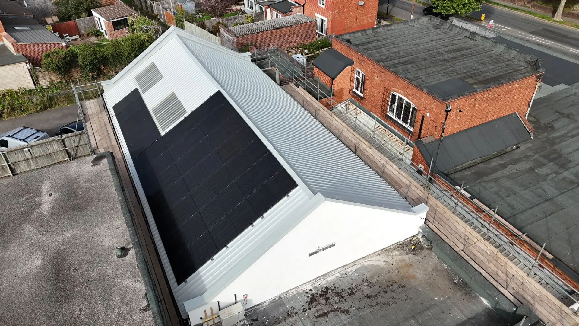 The same commercial building after re-roofing with new white profiled metal sheets, rooflights and solar panels