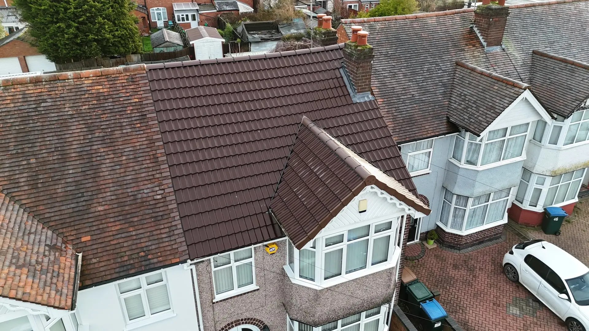 The same terraced house after re-roofing with new brown interlocking tiles, dry ridge and new bay gable finish
