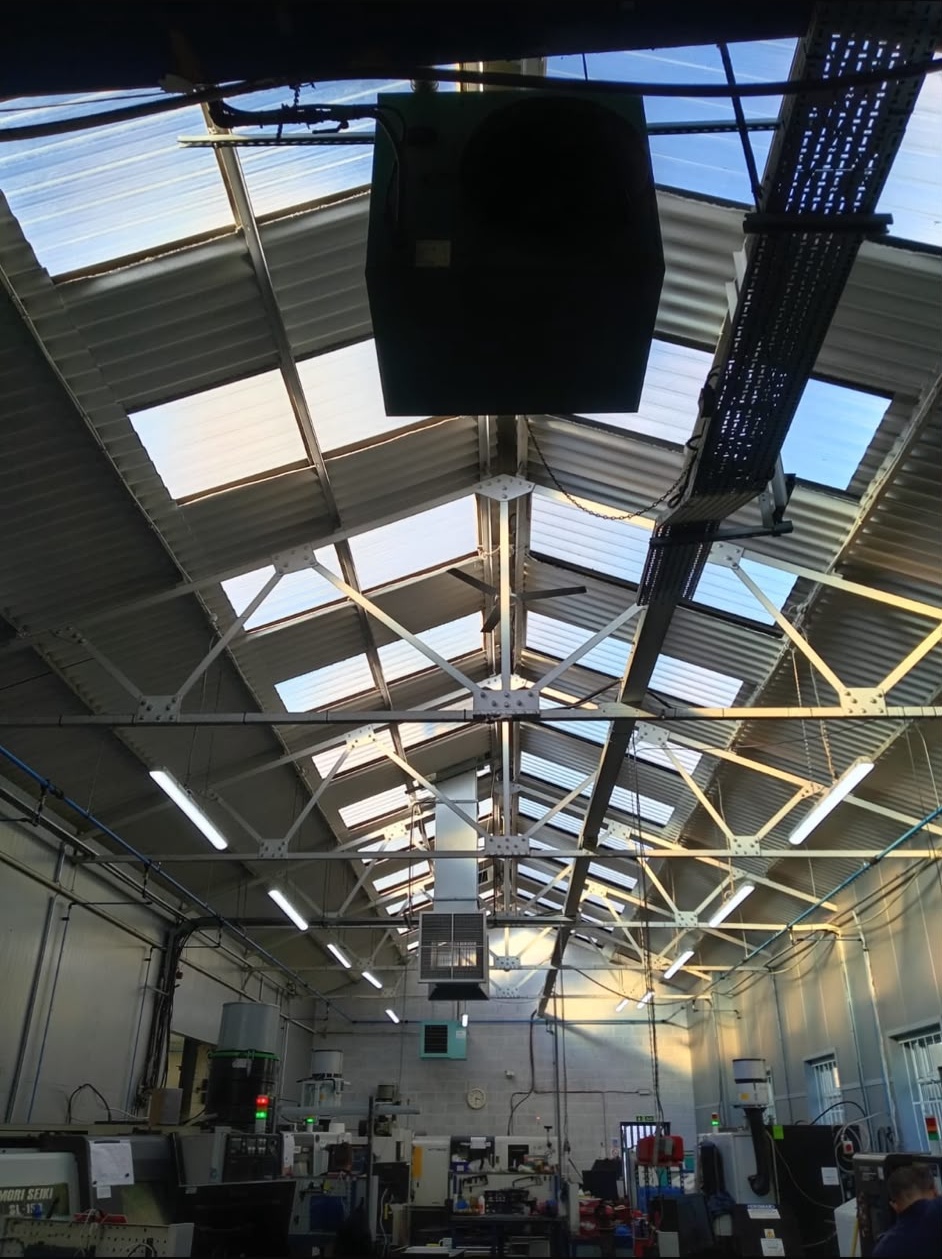 Factory interior showing underside of industrial roof with skylights and steel trusses